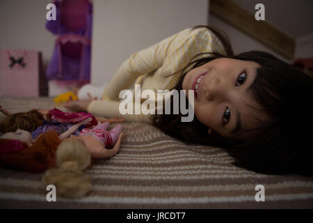 Portrait of girl with toys relaxing on bed at home Stock Photo
