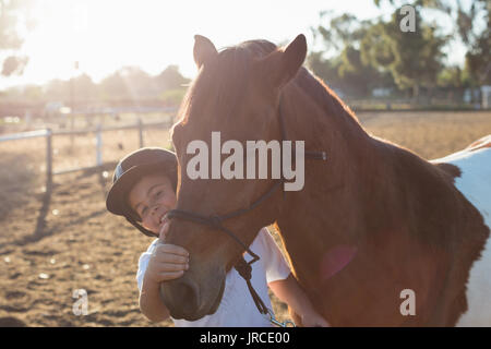 Rider boy caressing a horse in the ranch on a sunny day Stock Photo