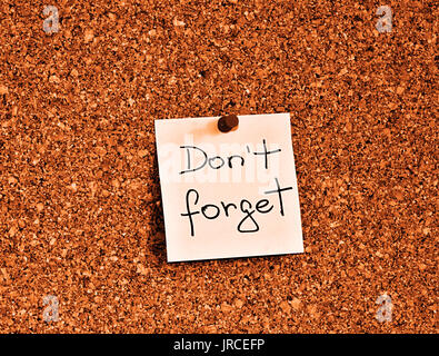 Cork notice board with one yellow sticky note pad with text please do not forget Stock Photo