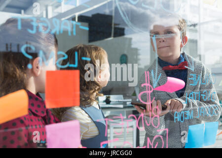 Business people analyzing data on window at office seen through glass Stock Photo