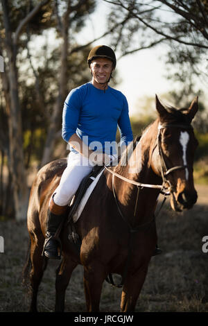 Portrait Of Confident Male Jockey With Horse Standing On Field And 