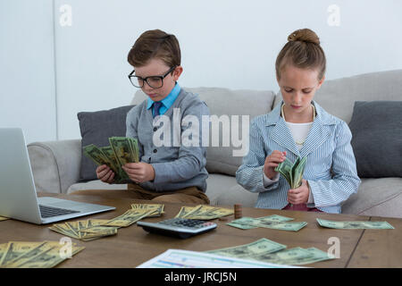 Colleagues counting currency while sitting on sofa at office Stock Photo