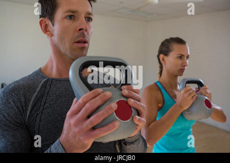 Dedicated athletes exercising with kettlebells in club Stock Photo