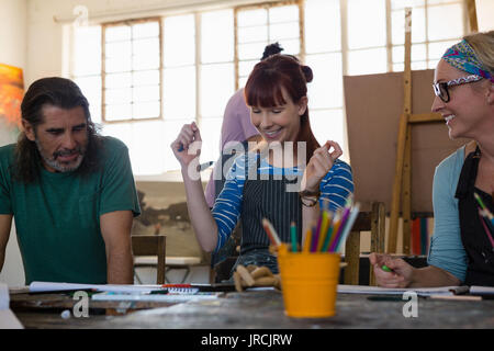 Happy adult students looking at painting while sitting in art class Stock Photo