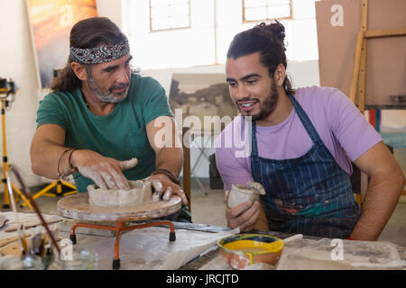 Man looking at teacher explaining to make clay structure pottery wheel in art class Stock Photo