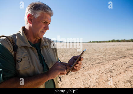 Man using digital tablet while standing on landscape Stock Photo