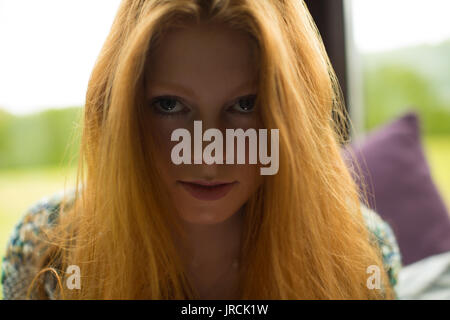 Close up portrait of young woman with redhead sitting at home Stock Photo