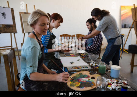 Teacher guiding students for painting in art class Stock Photo