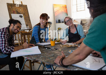Happy adult students talking while practicing in art class Stock Photo