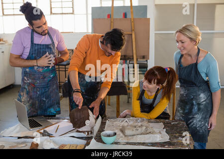 Male teacher showing sculpture to adult student in art class Stock Photo