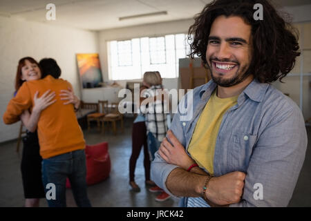 Portrait of smiling man with friends embracing in background while standing at art class Stock Photo