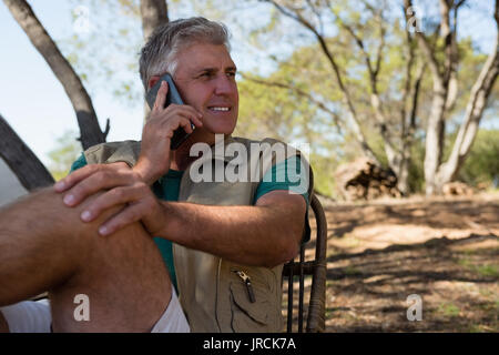 Mature man looking away while talking on phone at campsite Stock Photo
