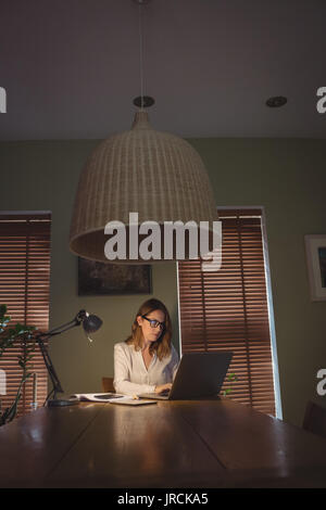 Woman using laptop in drawing room at home Stock Photo
