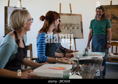 Happy teacher looking at adult students in art class Stock Photo