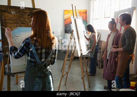 Adult students painting while standing in art studio Stock Photo