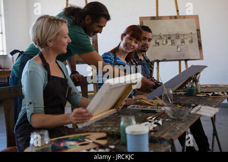 Teacher assisting student for painting in art class Stock Photo