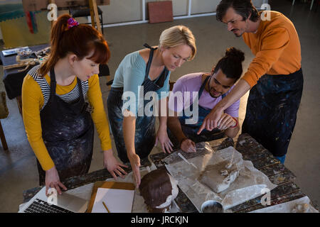 High angle view of teacher showing sculpture to adult student in art class Stock Photo