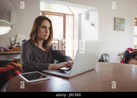 Woman using laptop in drawing room at home Stock Photo