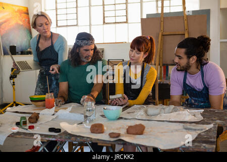 Teacher holding laptop while guiding student in art class Stock Photo