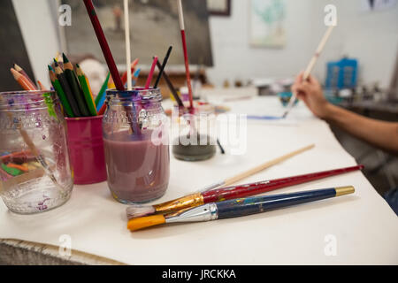 Close-up of various brushes and color pencil in pen holder at drawing class Stock Photo