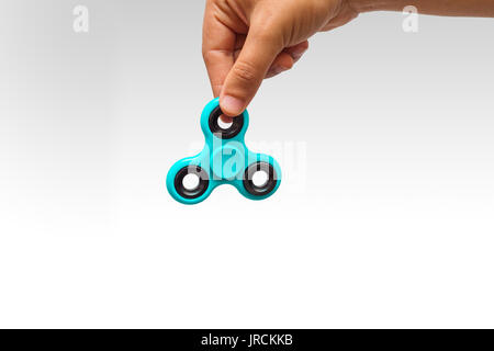 close-up of a young man playing with a fidget spinner, on isolated background Stock Photo