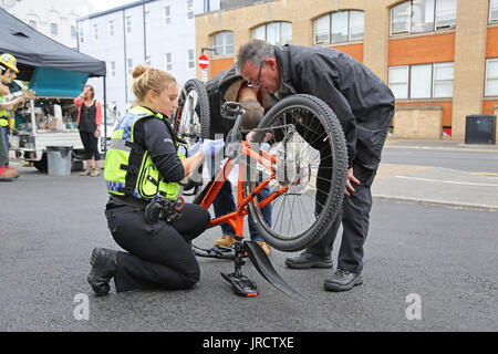 A bicycle registration event in Cambridge, UK. A female police officer security marks a bike whilst details are recorded by a colleague. Stock Photo