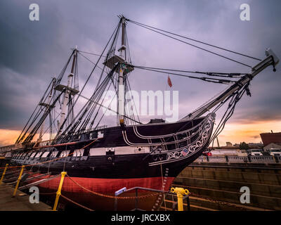 USS Constitution docked At Boston Harbor in Charlestown, Massachusetts, USA with gorgeous Sunset in the background on a cloudy day. Stock Photo