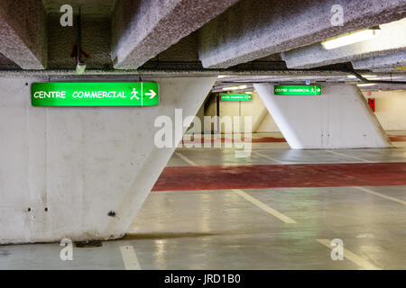 Luminous signs indicating the direction to the commercial center in an old decrepit underground parking lot. Stock Photo
