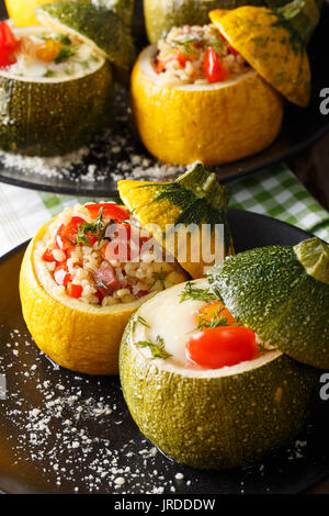 Green zucchini baked with eggs and yellow zucchini stuffed with bulgur close-up on a plate. vertical Stock Photo