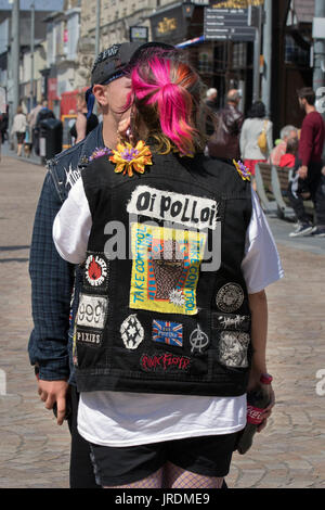 Oi Polloi decorated jacket on the street at the Blackpool Rebellion Punk festival.  Clothing, hairstyles, body modifications punk style jackets, denim and Scottish subculture.  Styles carried slogans, not logos and are modelled on bands like The Exploited to the dressed-down look of North American hardcore. The distinct social dress of other subcultures and art movements, including glam rock, and rude boys, have influenced punk fashion. Punk fashion has likewise influenced the styles of these groups, as well as those of popular culture. Many punks use clothing as a way of making a statement. Stock Photo