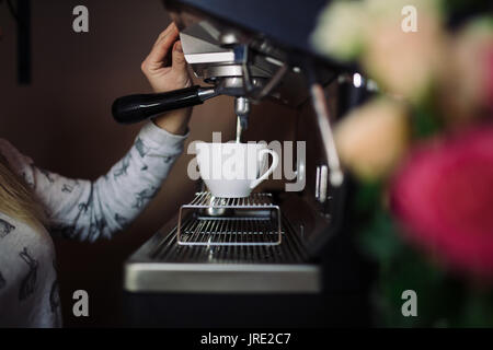 Coffee machine make espresso in cup. female barista preparing coffee in cafe Stock Photo