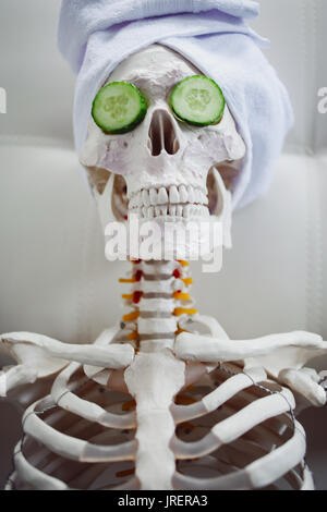 Skeleton in Spa salon with towel on her head and mask on her face, relaxes. An absurd concept, social parody. Take care of beauty and forget about inn Stock Photo