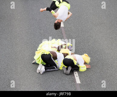 Stockton on Tees, north east England England, UK, 5th August, 2017. UK Weather: The sun shines on the community carnival parade at the Stockton International Riverside Festival (3rd-6th August). Local schools, community groups, musicians and dancers parade through the town on festival Saturday. PICTURED: An acrobat somersaults over fellow acrobats. Credit: ALAN DAWSON/Alamy Live News Stock Photo