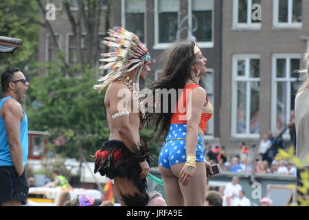 Revellers standing on boats beside the river Amstel celebrate Amsterdam gay prIde by wearing fancy dress and dancing as they watch the pride carnival floats pass by. Credit: Patricia Phillips/Alamy live news Stock Photo