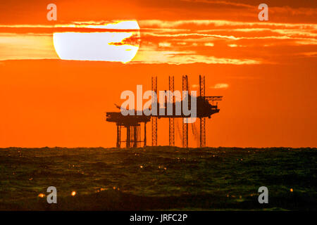 Southport, Merseyside, 5th August 2017. UK Weather.    After a sunny day over the north west of England, a stunning sunset nestles into the horizon behind the Hamilton oil rig off the Southport coastline.  The Douglas Complex is a 54-metre (177 ft) high system of three linked platforms in the Irish Sea, 24 kilometres off the North Wales coast. The Douglas oil field was discovered in 1990, and production commenced in 1996.  This accommodation module was formerly the Morecambe Flame jack-up drilling rig.  Credit: Cernan Elias/Alamy Live News Stock Photo