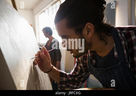 Close up of male artist painting on artist canvas in art class Stock Photo