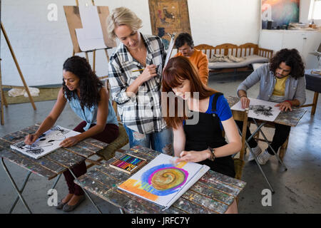 High angle view of teacher examining students painting at table in art class Stock Photo