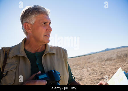 Mature man with camera looking away on landscape Stock Photo