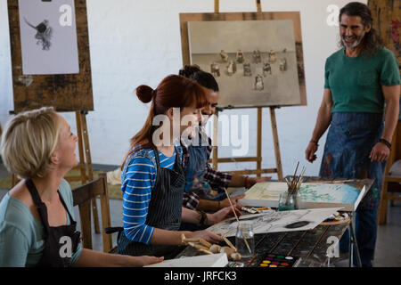 Smiling teacher looking at adult students in art class Stock Photo