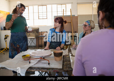 Adult student looking at teacher explaining while standing in art class Stock Photo