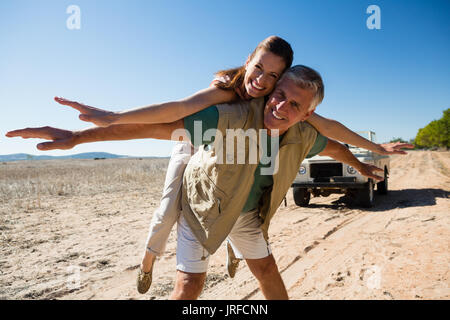 Portrait of happy playful couple on landscape during sunny day Stock Photo