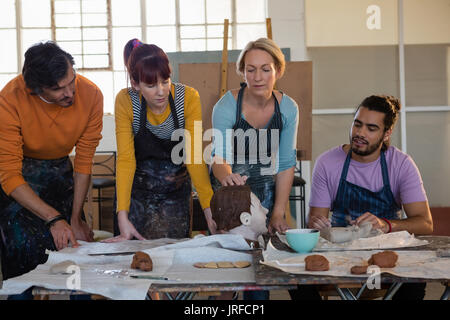 Female teacher showing sculpture to adult student in art class Stock Photo