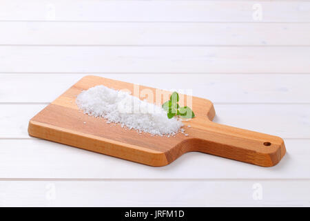 pile of coarse grained sea salt on wooden cutting board Stock Photo