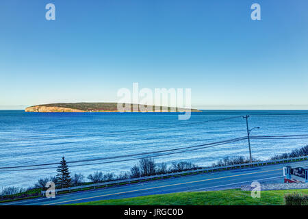 Perce, Canada - June 5, 2017: Bonaventure Island during sunset in Gaspe Peninsula, Quebec, Canada, Gaspesie region with blue water and hotel sign Stock Photo