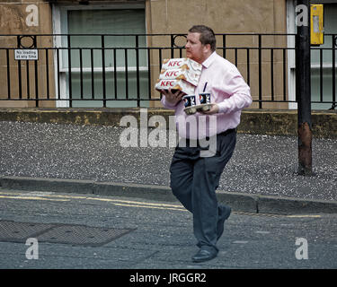 fat man lunchtime crossing road overloaded with junk food obese office worker KFC Pepsi Glasgow scotland Stock Photo