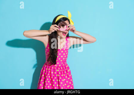 happy smiling woman holding fresh donut food as telescope looking at camera  isolated on blue background. Stock Photo