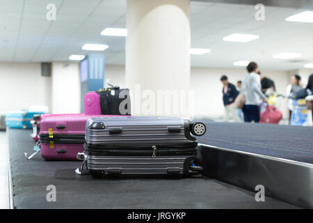 Wheeled suitcase on a luggage belt at the airport terminal. Stock Photo