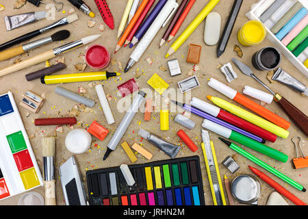colorful school supplies on recycled paper background: watercolor, colored pencils and markers, chalks, various paintbrushes, sharpener Stock Photo