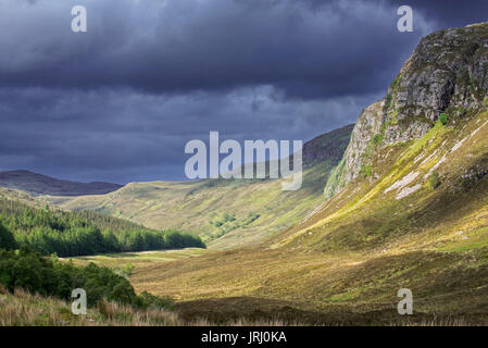 Mountain scenery showing dark rain clouds rolling in over sunny hillside and valley in Wester Ross, Scottish Highlands, Scotland, UK Stock Photo