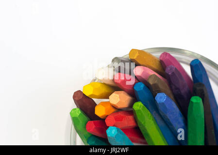multicolored crayons in cup on white paper Stock Photo